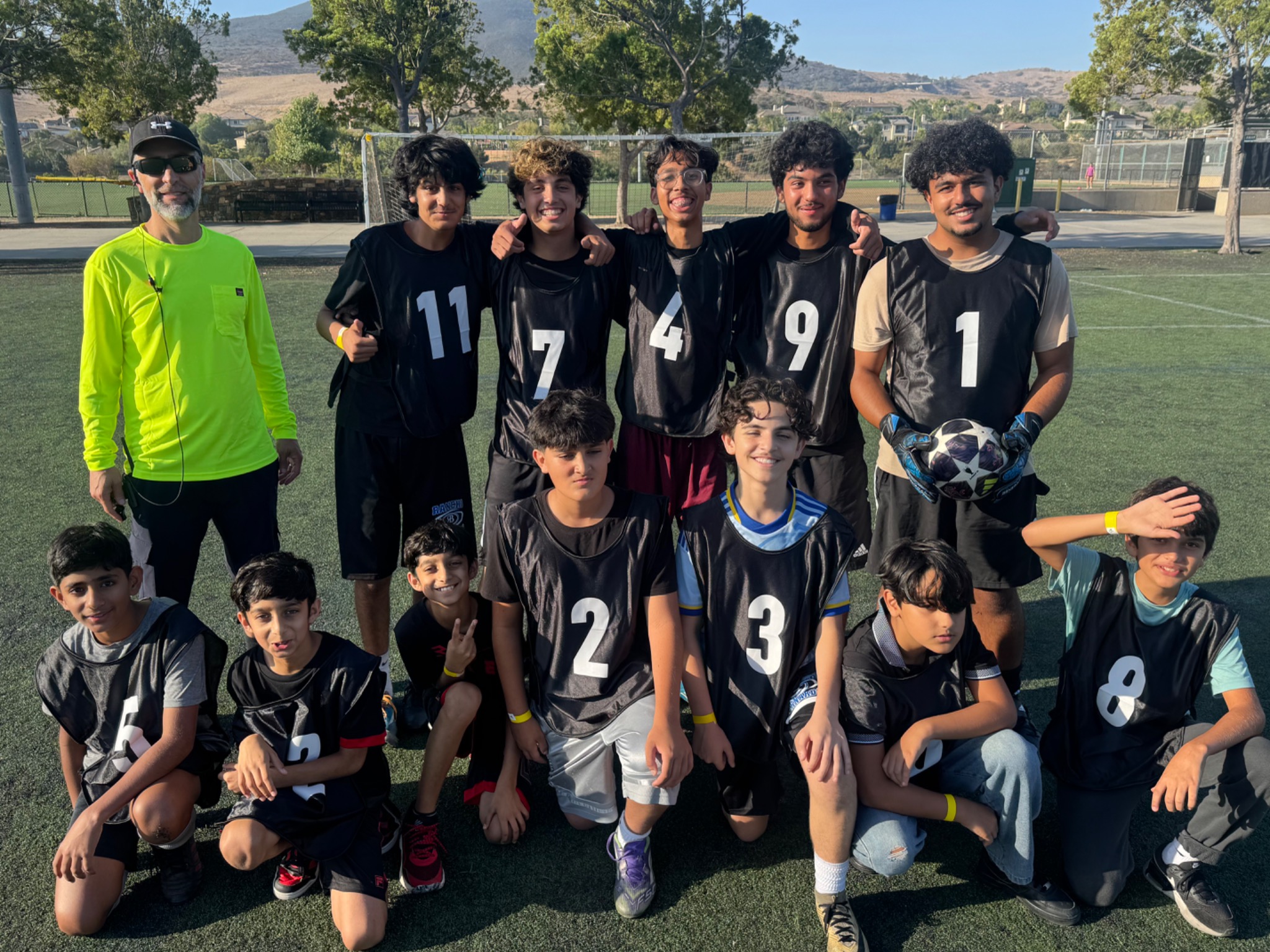Youth soccer players in black training bibs gathered on the field